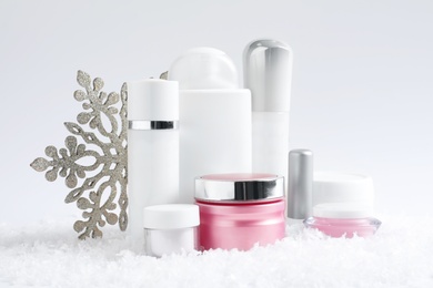 Photo of Set of cosmetic products and decorative snow on white background. Winter care