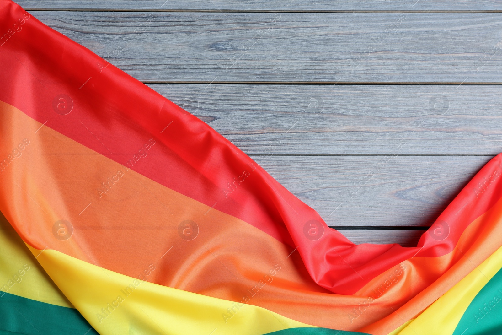 Photo of Bright rainbow gay flag on wooden background, top view with space for text. LGBT community