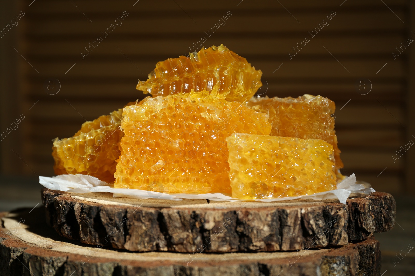 Photo of Natural honeycombs on stump against blurred background, closeup