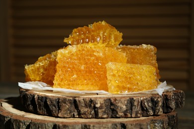 Photo of Natural honeycombs on stump against blurred background, closeup