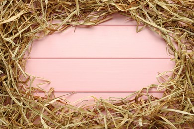 Frame of dried hay on pink wooden background, flat lay. Space for text