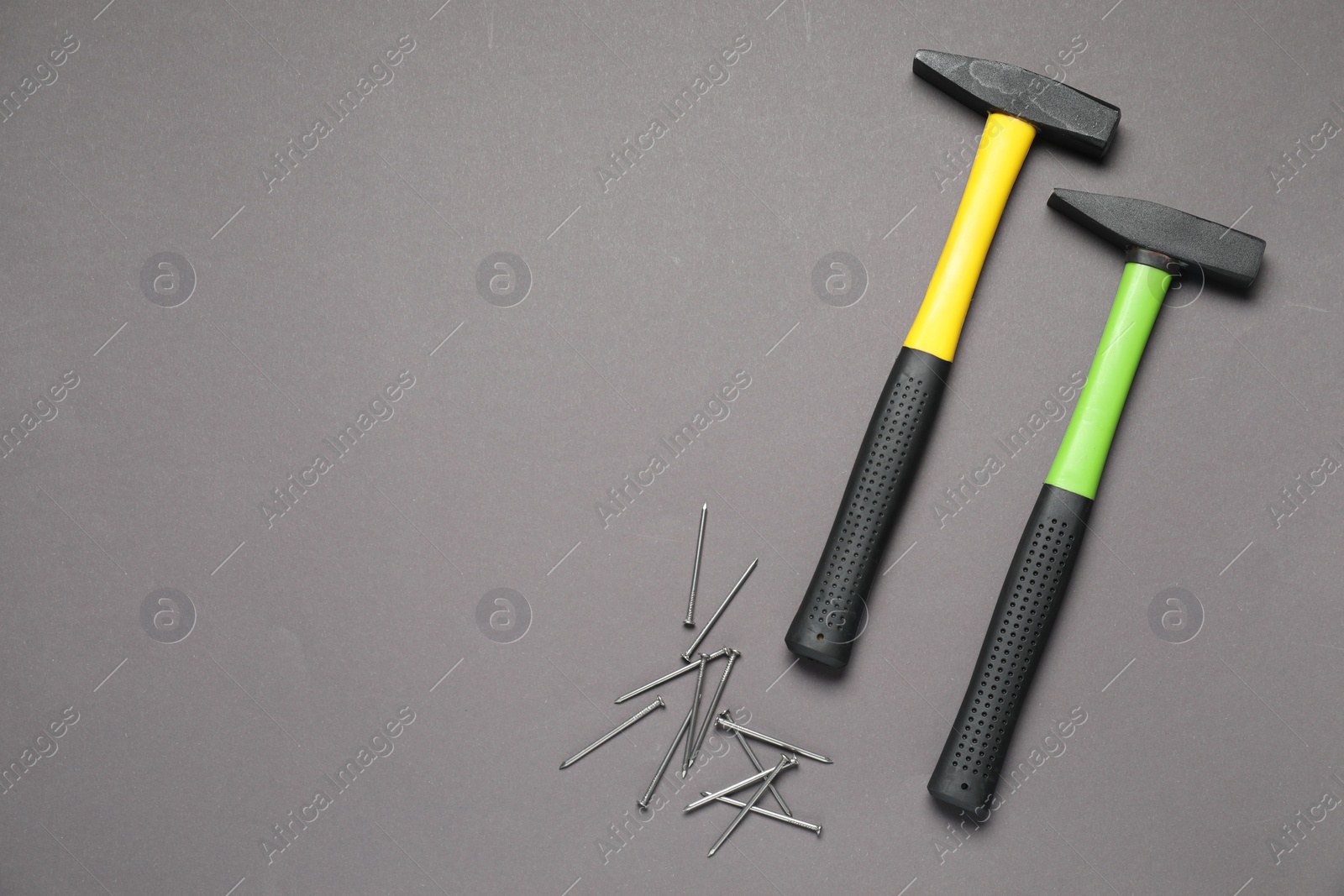 Photo of Hammer and metal nails on grey background, top view. Space for text