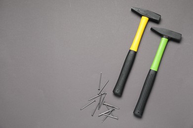 Hammer and metal nails on grey background, top view. Space for text