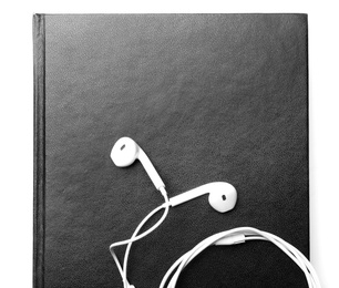 Photo of Bible and earphones on white background, top view. Religious audiobook