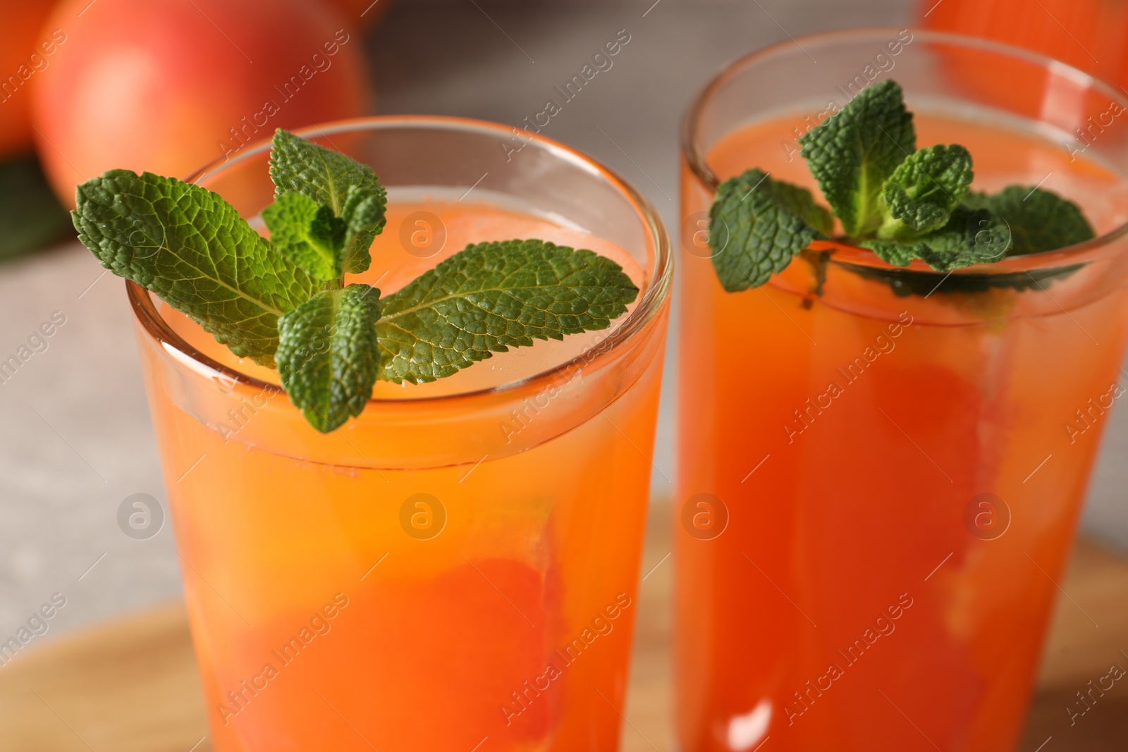 Photo of Tasty freshly made grapefruit juice with mint on table, closeup