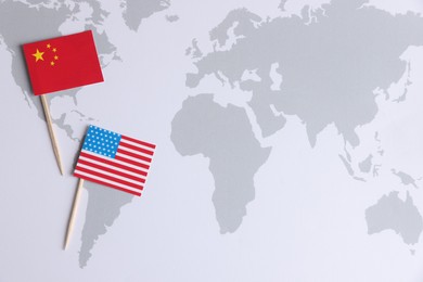Photo of American and Chinese flags on world map, top view with space for text. Trade war concept