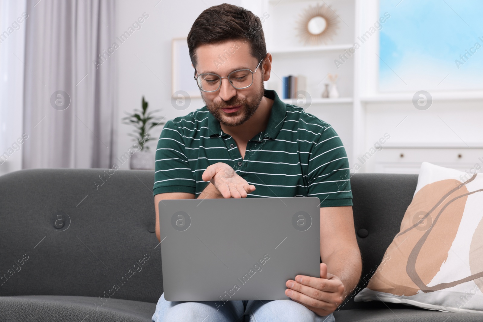 Photo of Man blowing kiss during video chat via laptop at home. Long-distance relationship