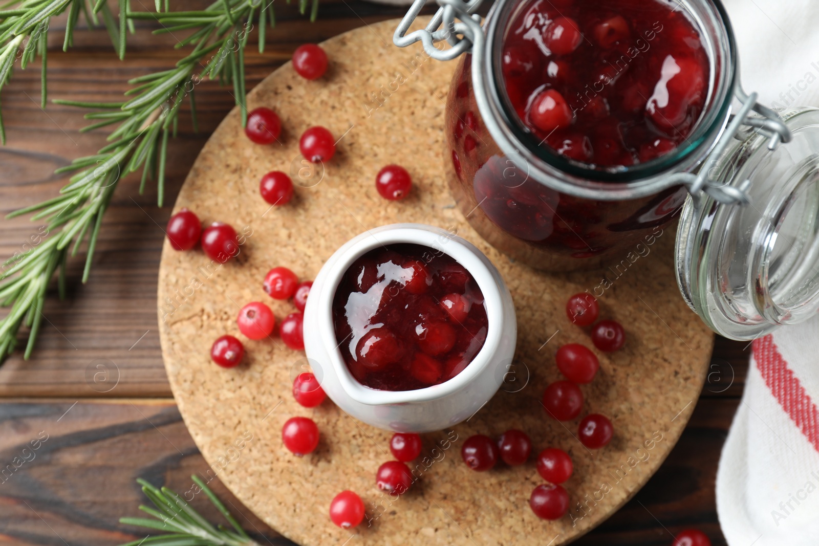 Photo of Cranberry sauce, fresh berries and rosemary on wooden table, flat lay