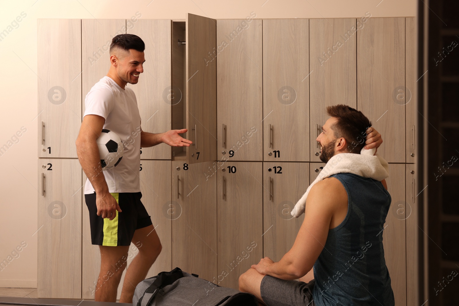 Photo of Handsome athletic men talking in locker room