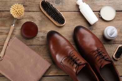 Photo of Flat lay composition with shoe care accessories and footwear on wooden background