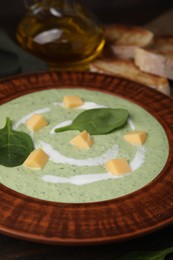 Photo of Delicious spinach cream soup with leaves and cheese in bowl on wooden table, closeup