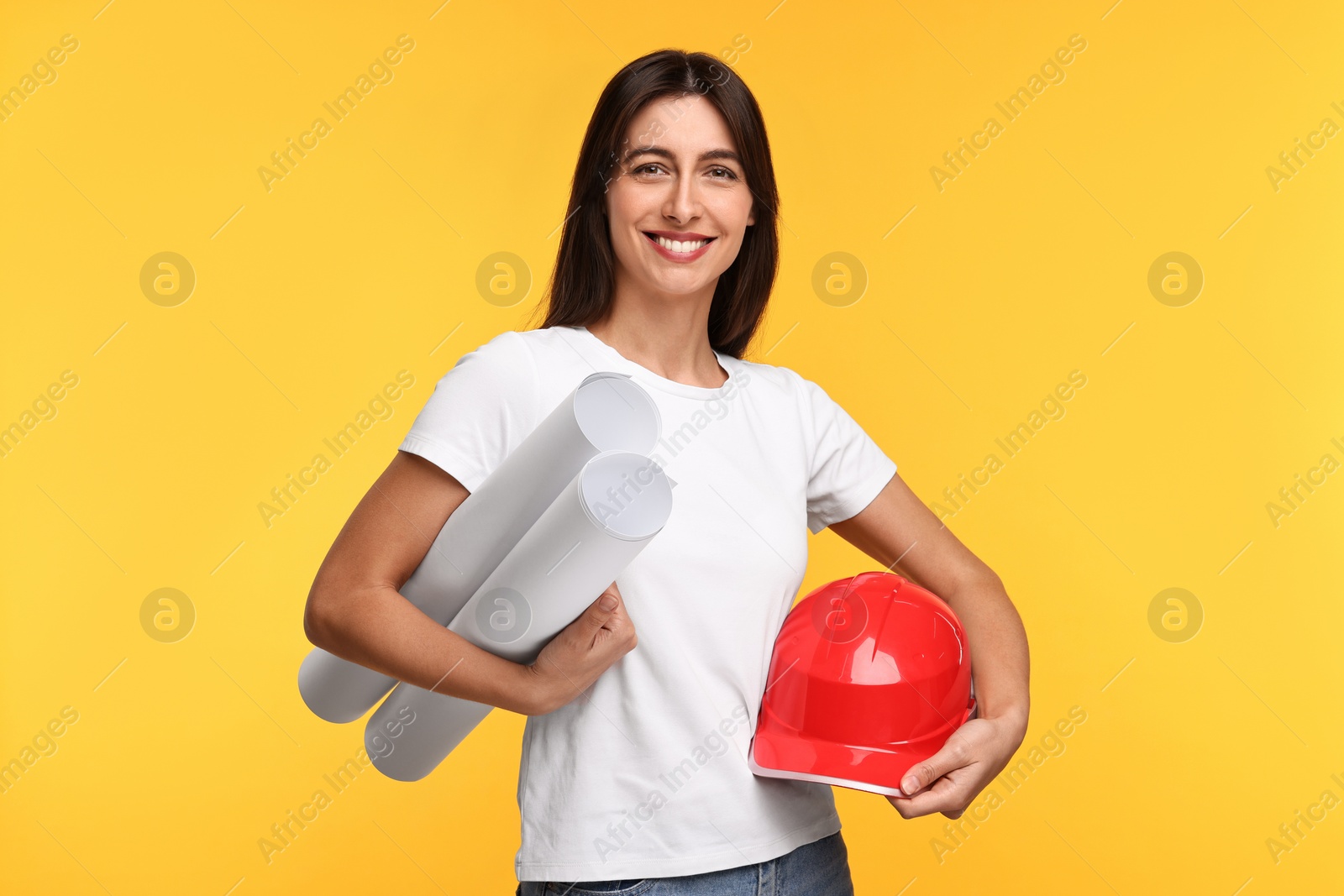 Photo of Architect with hard hat and drafts on yellow background