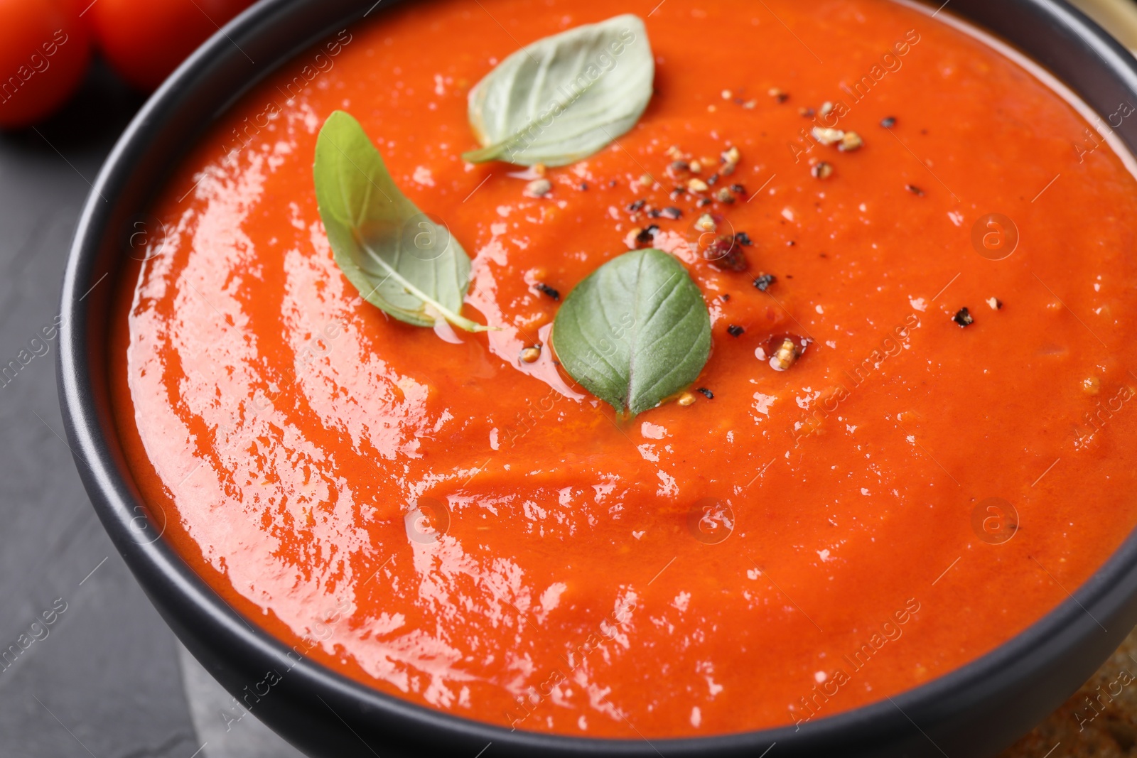 Photo of Delicious tomato cream soup on black table, closeup