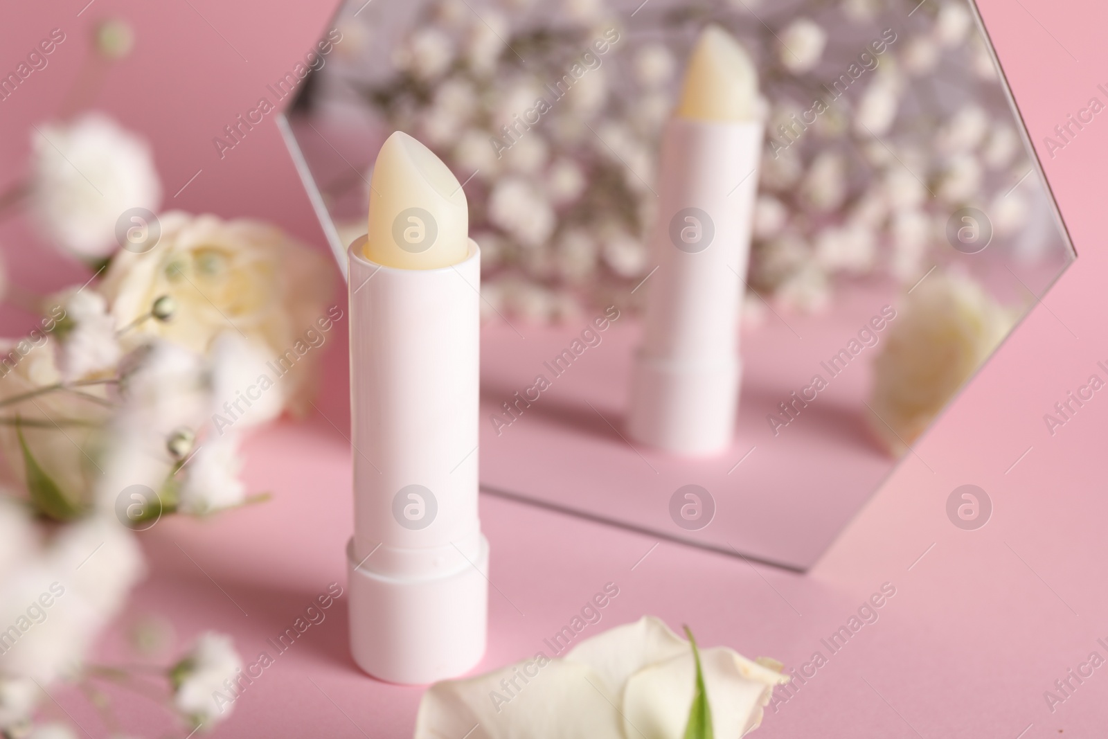 Photo of Stylish presentation of lip balm on pink background, closeup. Space for text