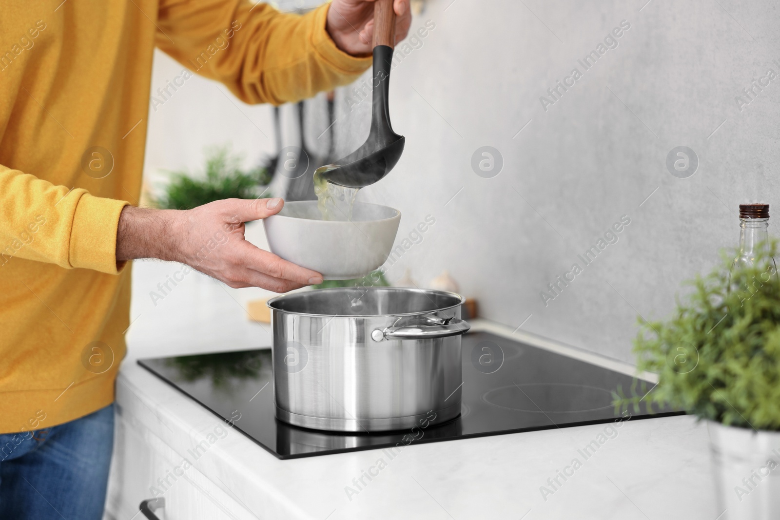 Photo of Man pouring delicious soup into bowl in kitchen, closeup