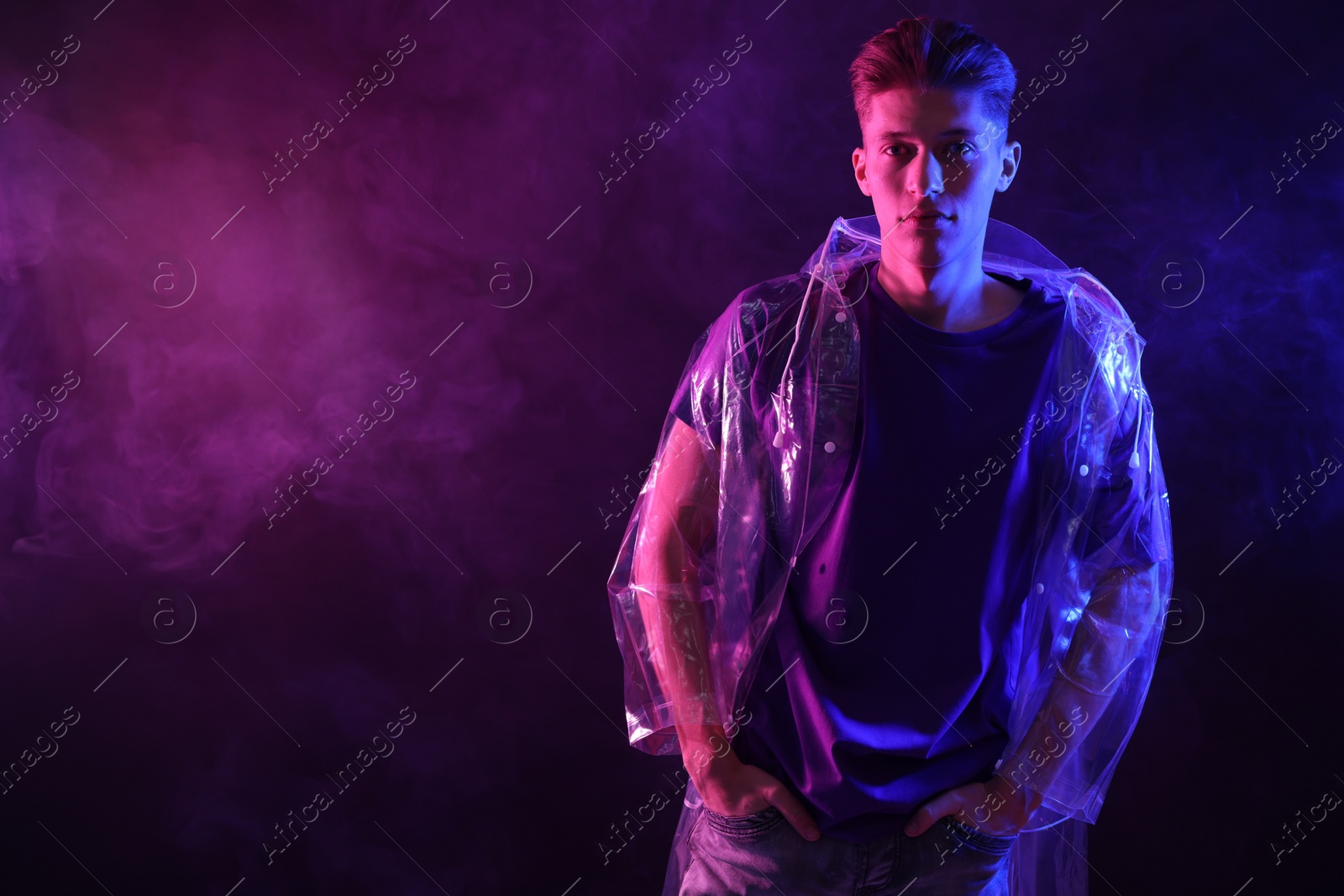 Photo of Young man wearing clear coat in neon lights with smoke effect. Space for text