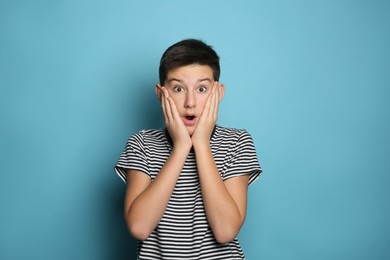 Emotional teenage boy on light blue background