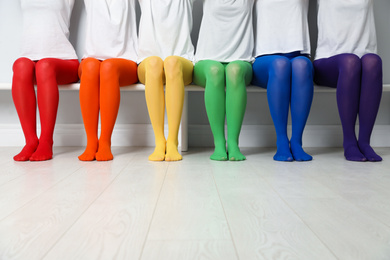 Photo of Women in different colorful tights sitting on bench, closeup