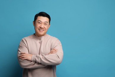 Portrait of happy man on light blue background. Space for text