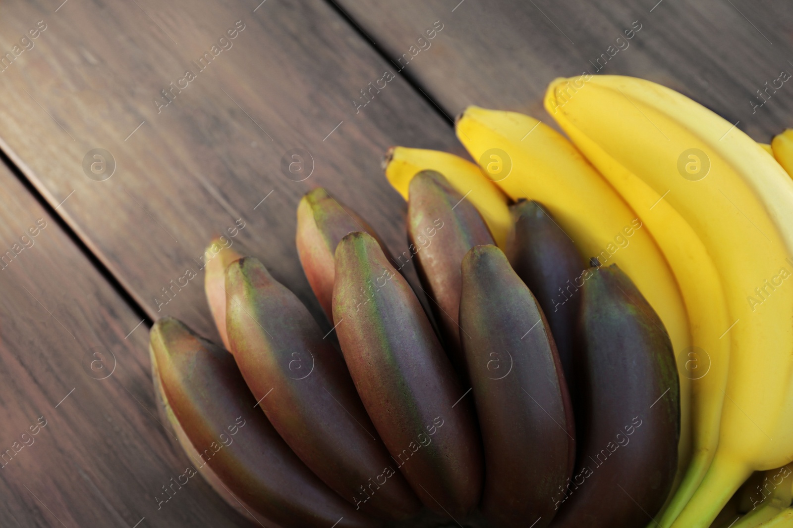 Photo of Tasty purple and yellow bananas on wooden table, closeup