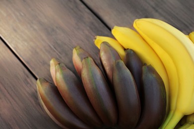 Photo of Tasty purple and yellow bananas on wooden table, closeup