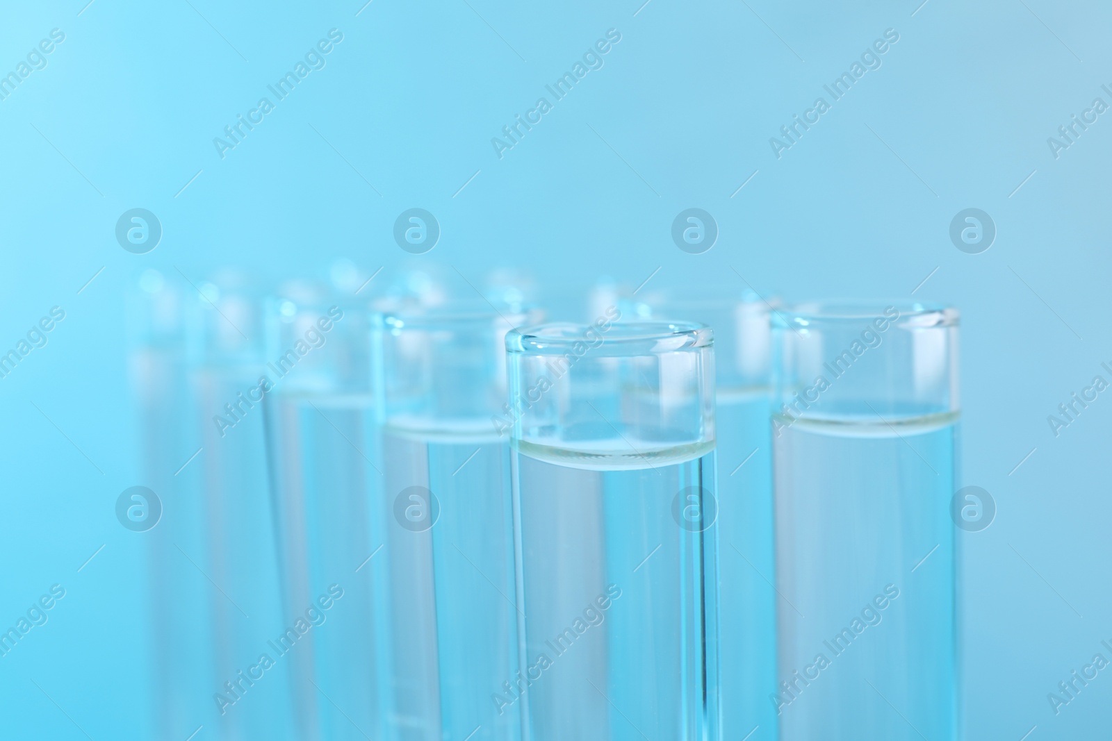 Photo of Laboratory analysis. Test tubes with liquid samples on light blue background, closeup