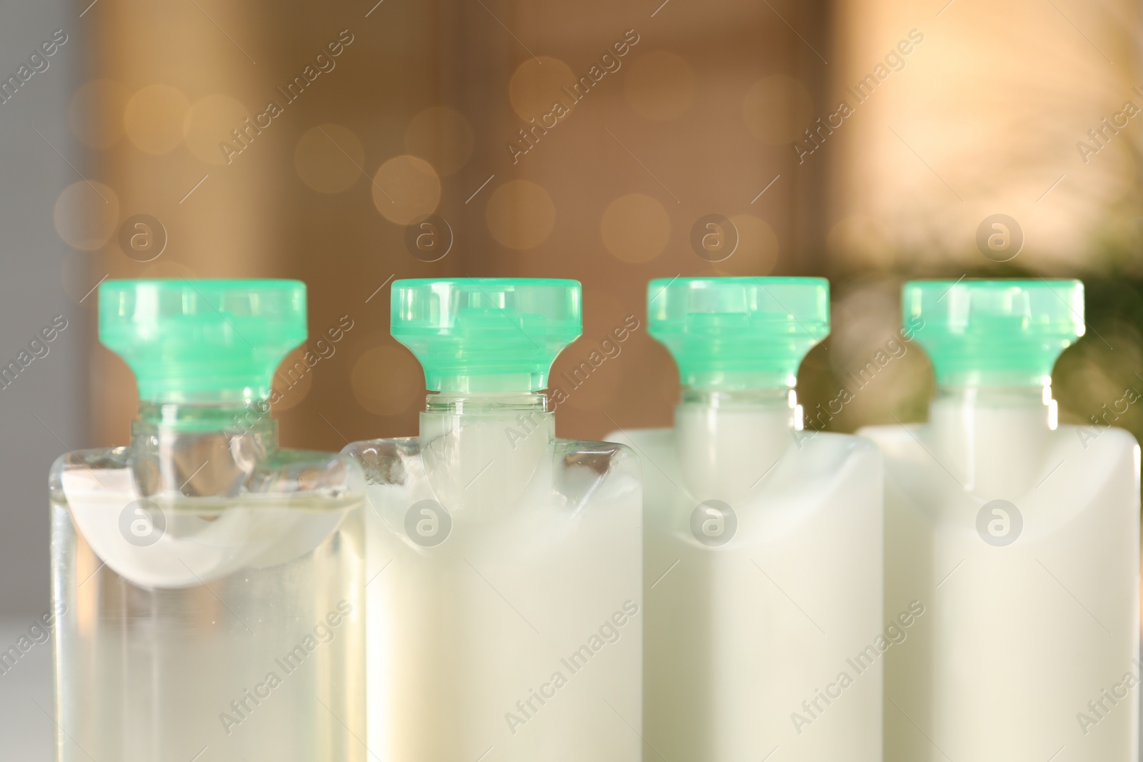 Photo of Mini bottles of cosmetic products on blurred background, closeup