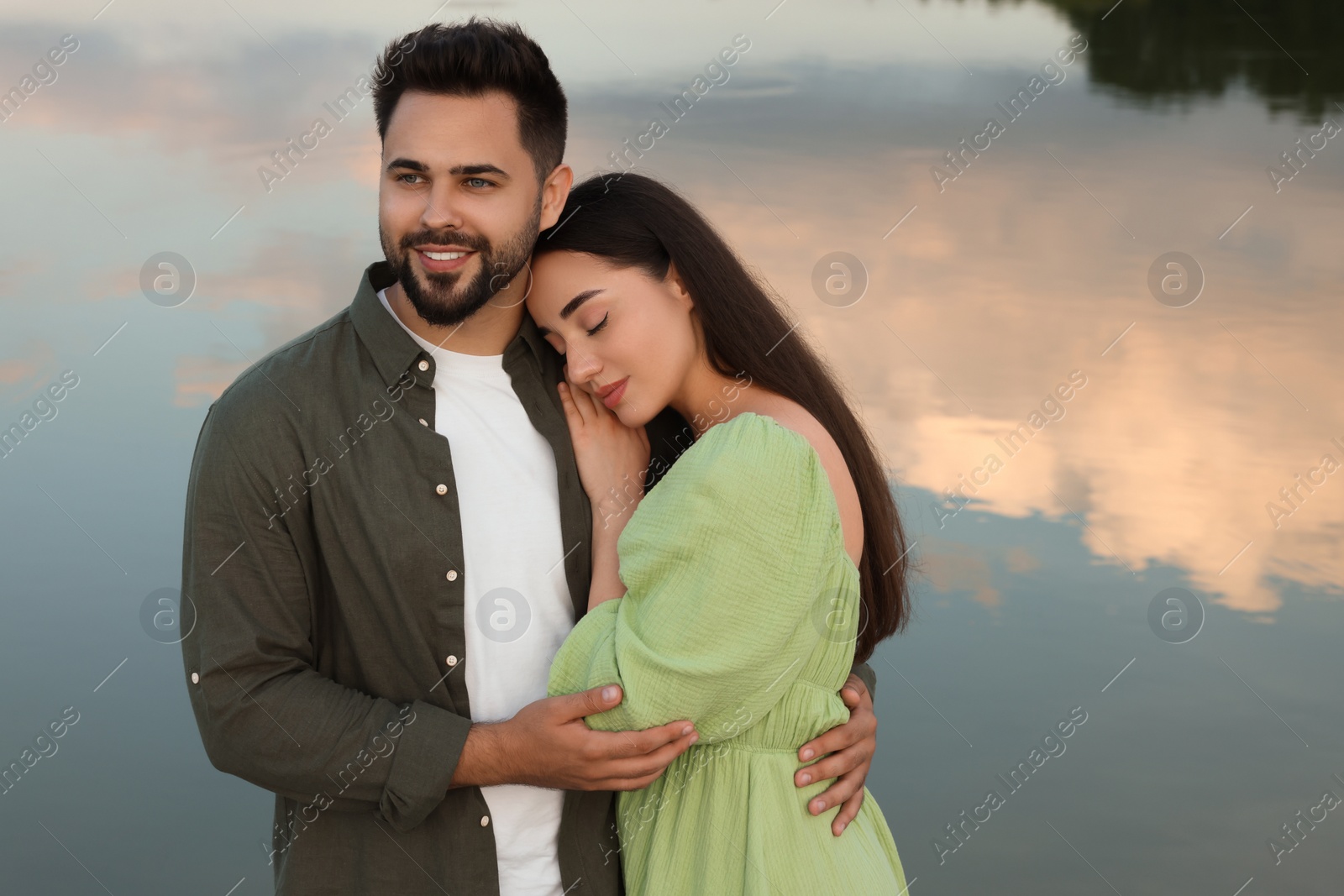 Photo of Romantic date. Beautiful couple spending time together near lake, space for text