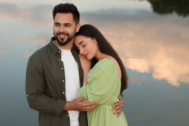 Photo of Romantic date. Beautiful couple spending time together near lake, space for text