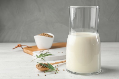 Photo of Composition with glassware of hemp milk on white wooden table against grey background