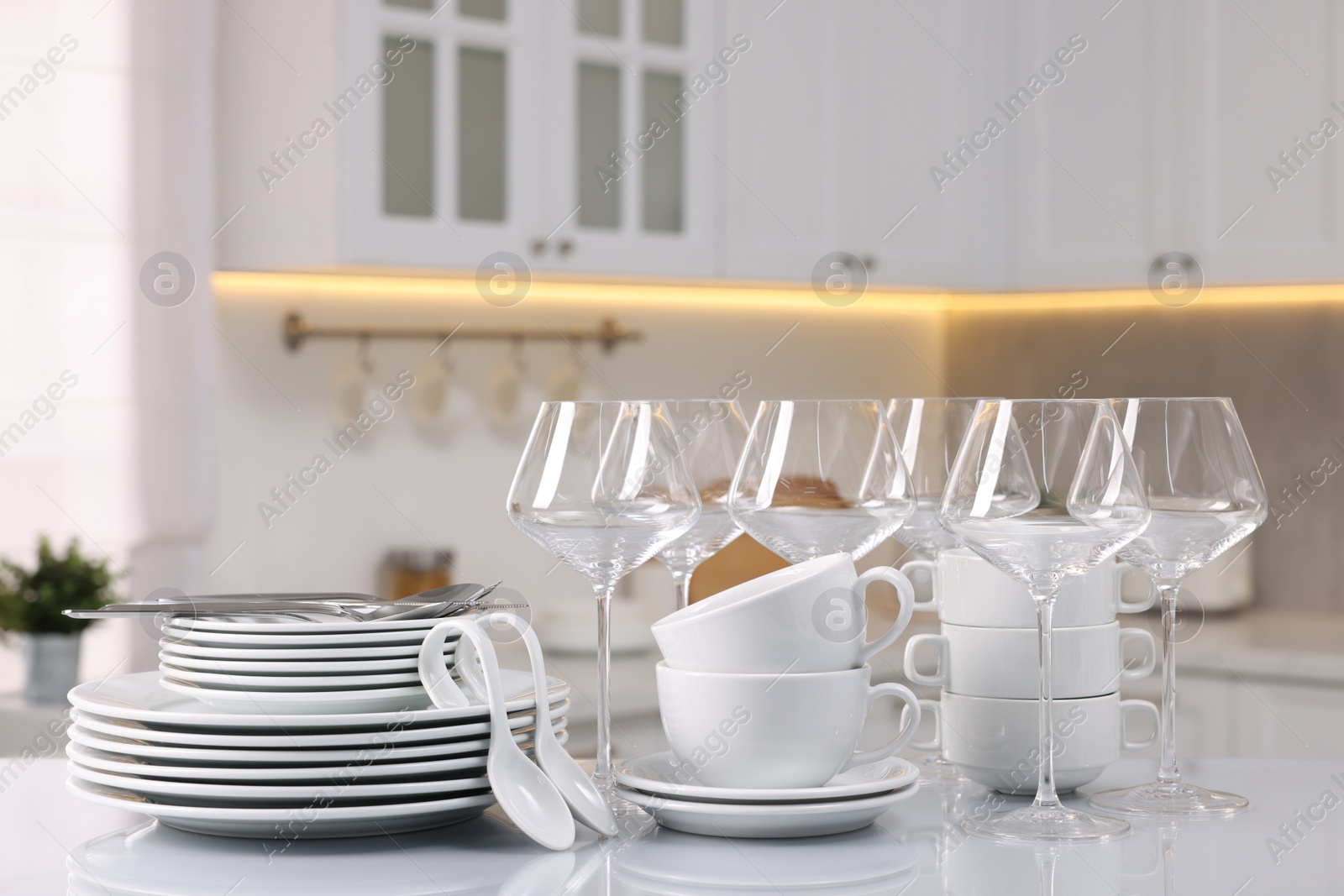 Photo of Set of clean dishware, glasses and cutlery on table in kitchen