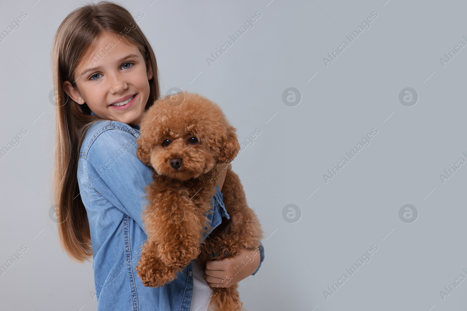Photo of Little child with cute puppy on light grey background, space for text. Lovely pet