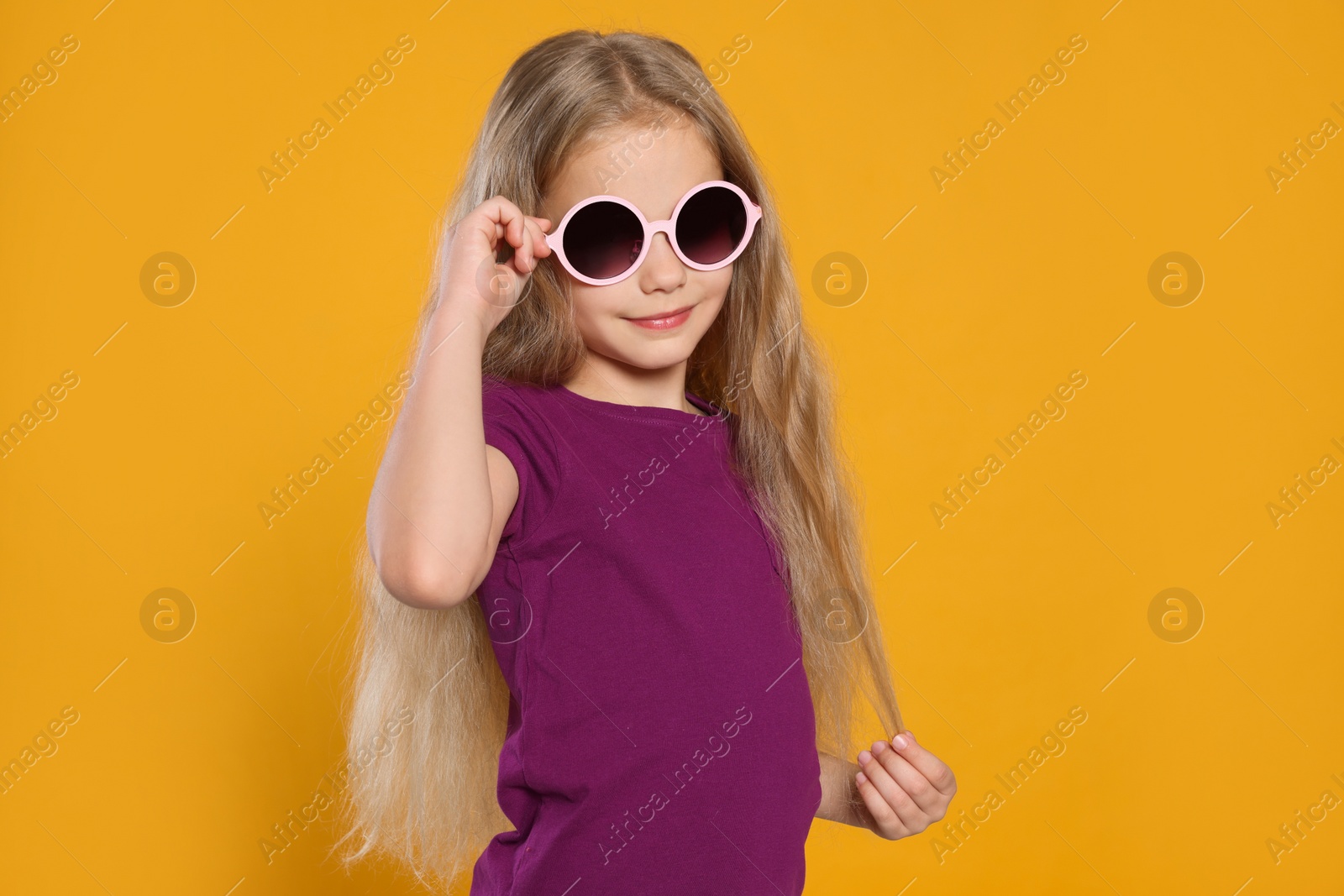 Photo of Girl in stylish sunglasses on orange background