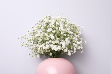 Photo of Bouquet of white gypsophila in ceramic vase on light background, top view