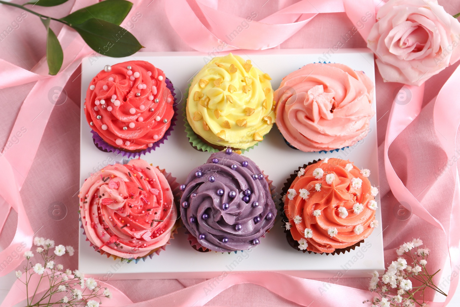 Photo of Delicious cupcake with bright cream on pink fabric, top view