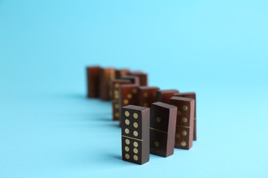 Photo of Row of wooden domino tiles on light blue background
