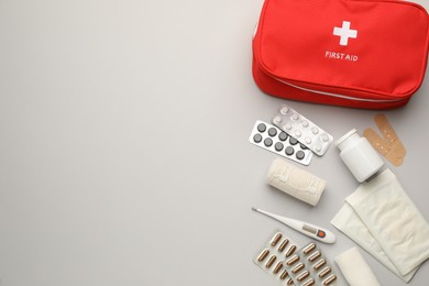 Flat lay composition with first aid kit on light grey background, space for text