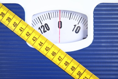 Photo of Scales with tape measure, closeup view. Diet and weight loss