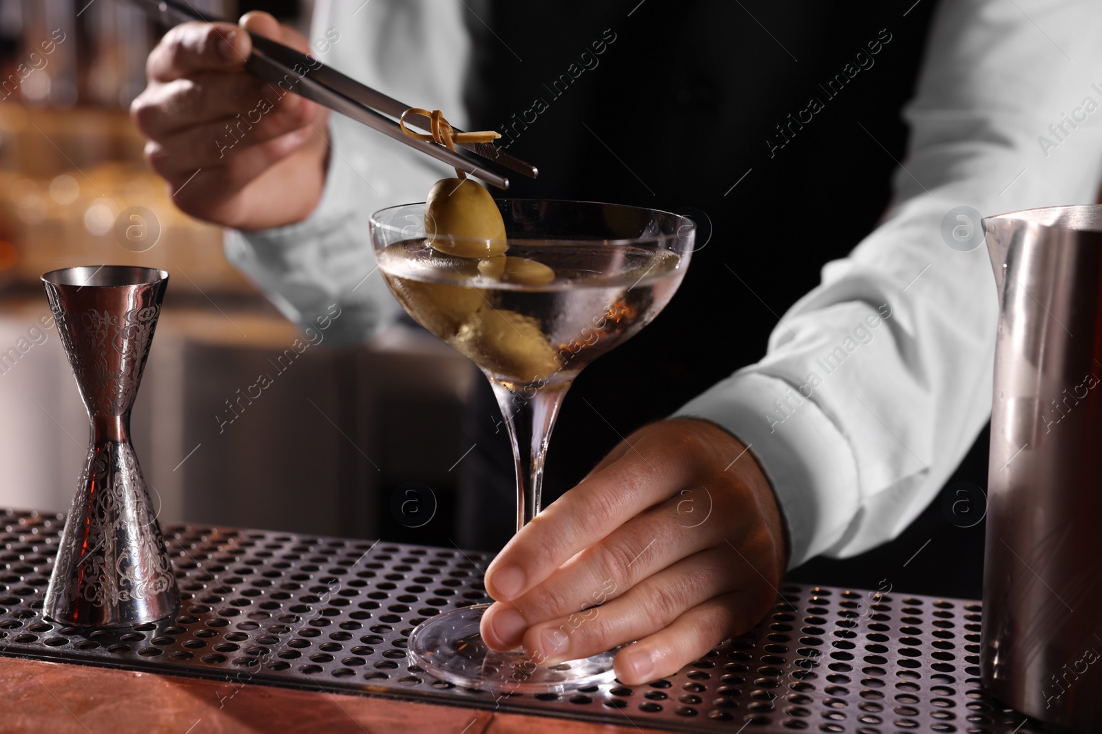 Photo of Bartender preparing fresh Martini cocktail at bar counter, closeup