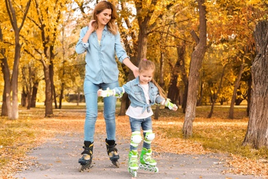 Photo of Mother and her daughter roller skating in autumn park