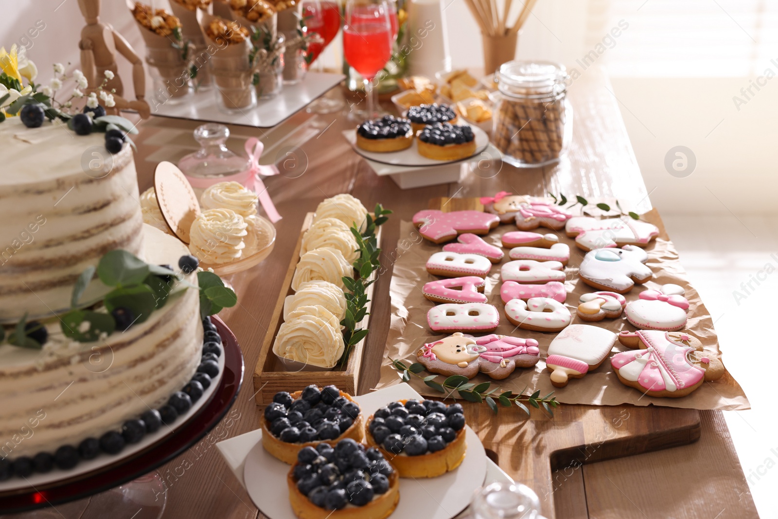 Photo of Baby shower party. Different delicious treats on wooden table indoors