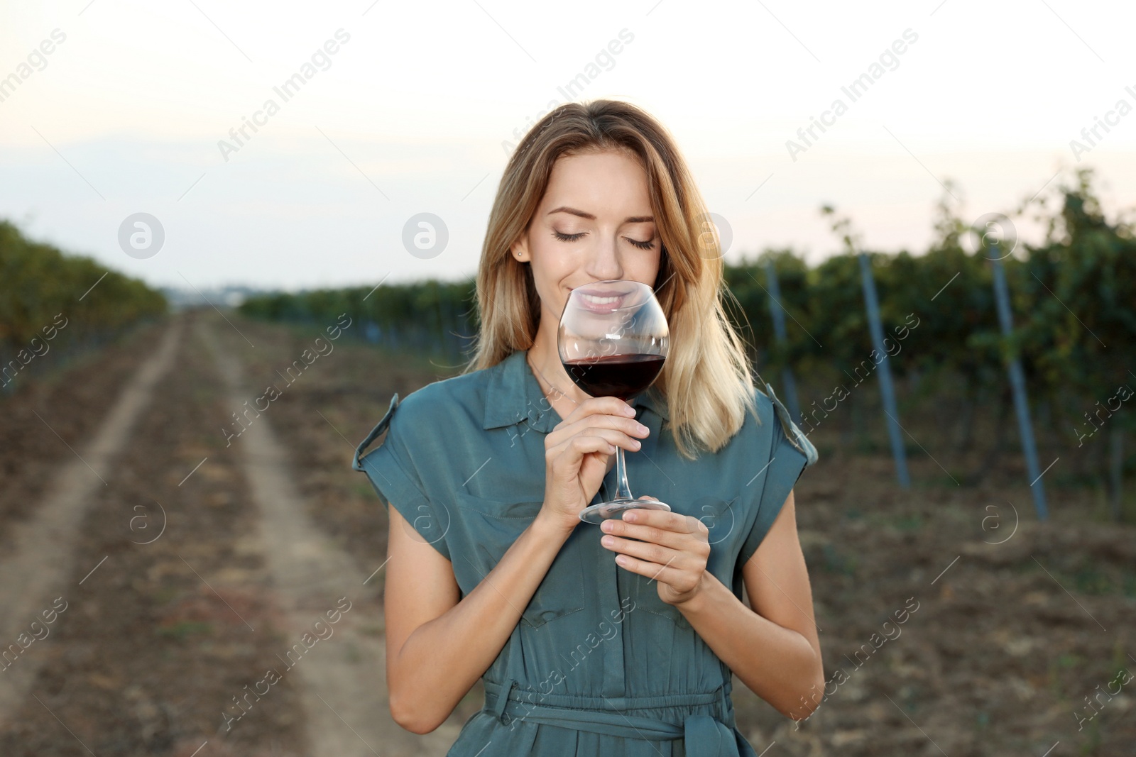 Photo of Young beautiful woman enjoying wine at vineyard