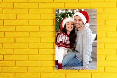 Image of Canvas with printed photo happy couple wearing Santa hats on yellow brick wall, space for text