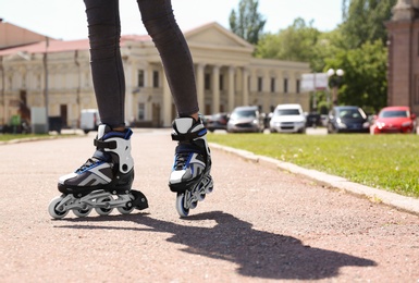 Photo of Woman with modern inline roller skates in city park, closeup