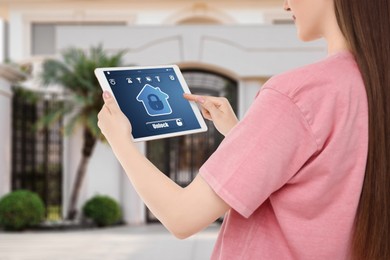 Woman using home security system application on tablet outdoors, closeup