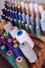 Photo of Set of colorful threads on stand in tailor studio, closeup