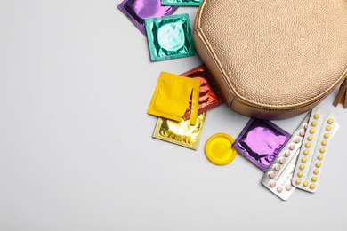 Photo of Flat lay composition with birth control pills and condoms on light background, space for text. Safe sex concept