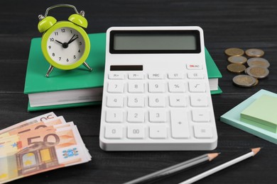 Calculator, money, notebook, alarm clock, sticky notes and pencils on black table. Retirement concept