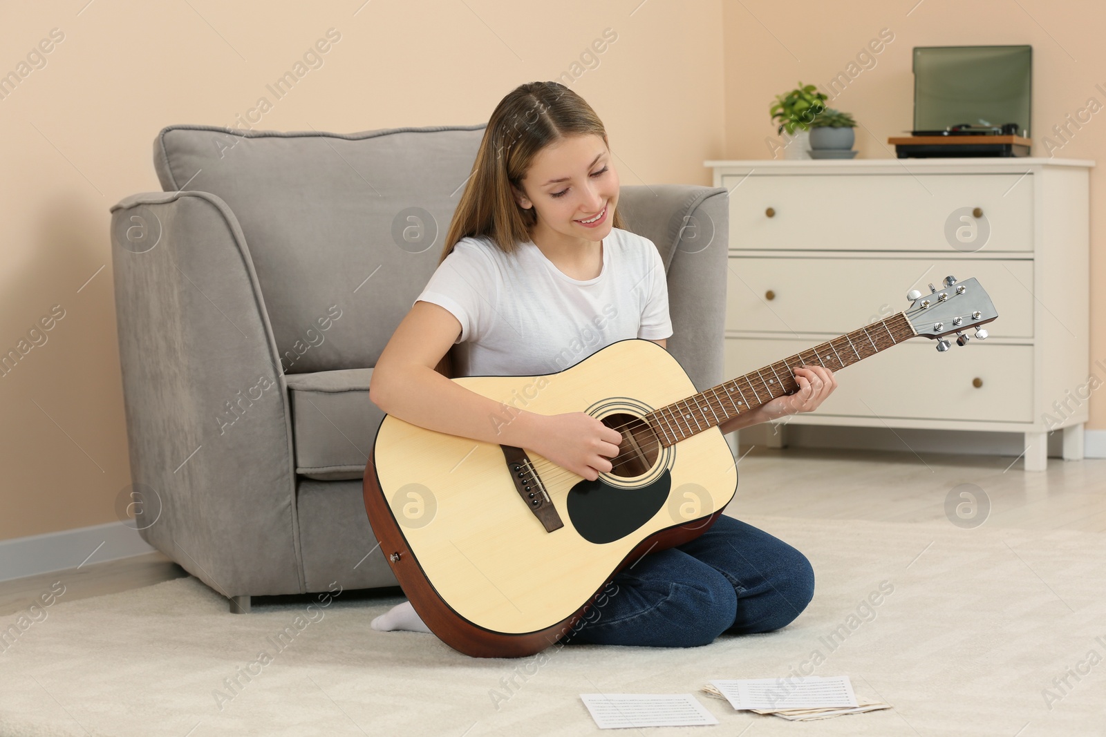 Photo of Teenage girl playing acoustic guitar in room