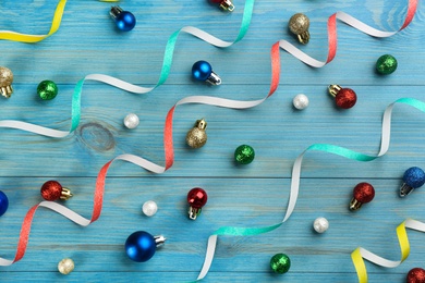 Photo of Colorful serpentine streamers and Christmas balls on blue background, flat lay